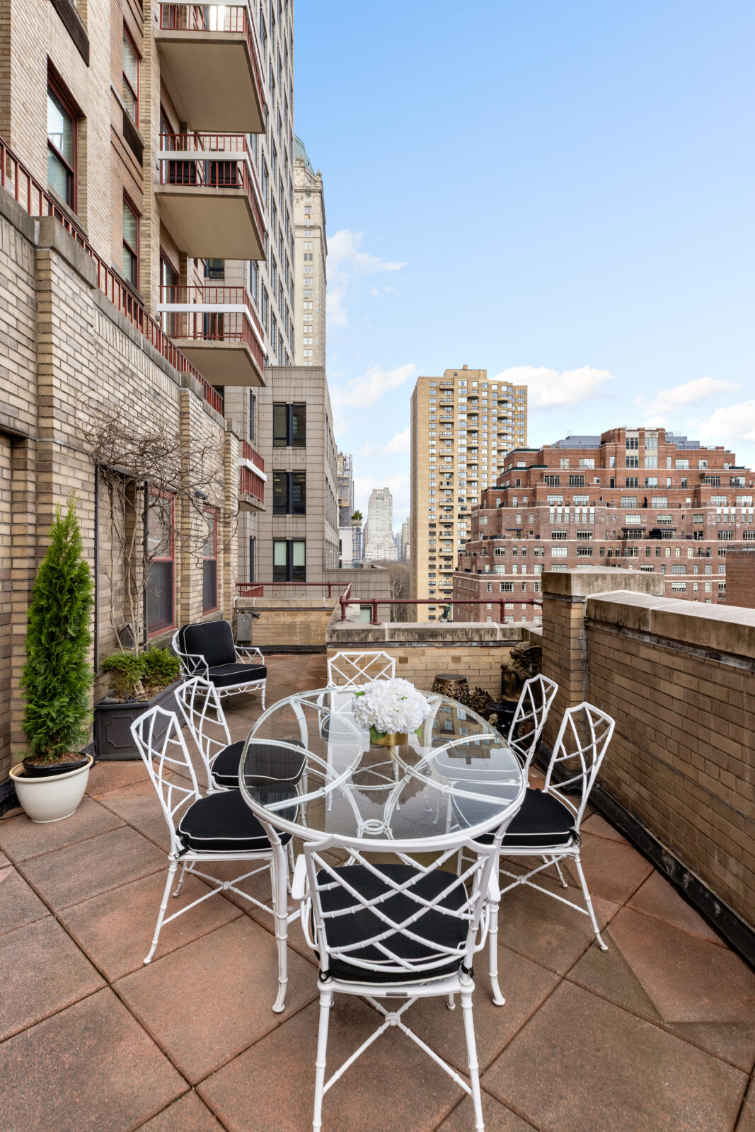 The terrace is framed by planted edges and divided into multiple outdoor areas, including a dining space set between the surrounding Upper East Side buildings.