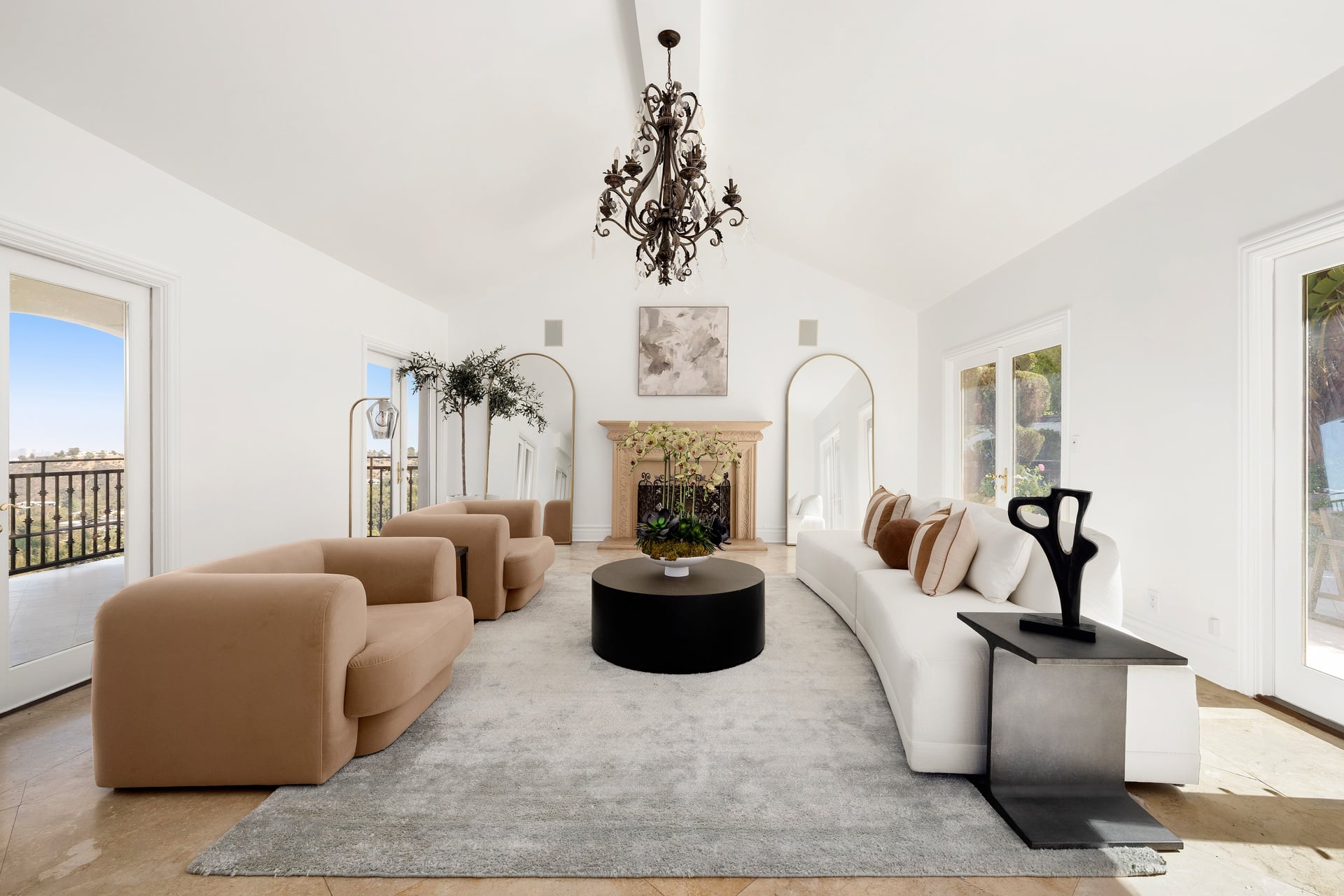 The formal living room stretches beneath a double-height vaulted ceiling, with a cast-stone fireplace centered along the far wall and the seating arranged around it.