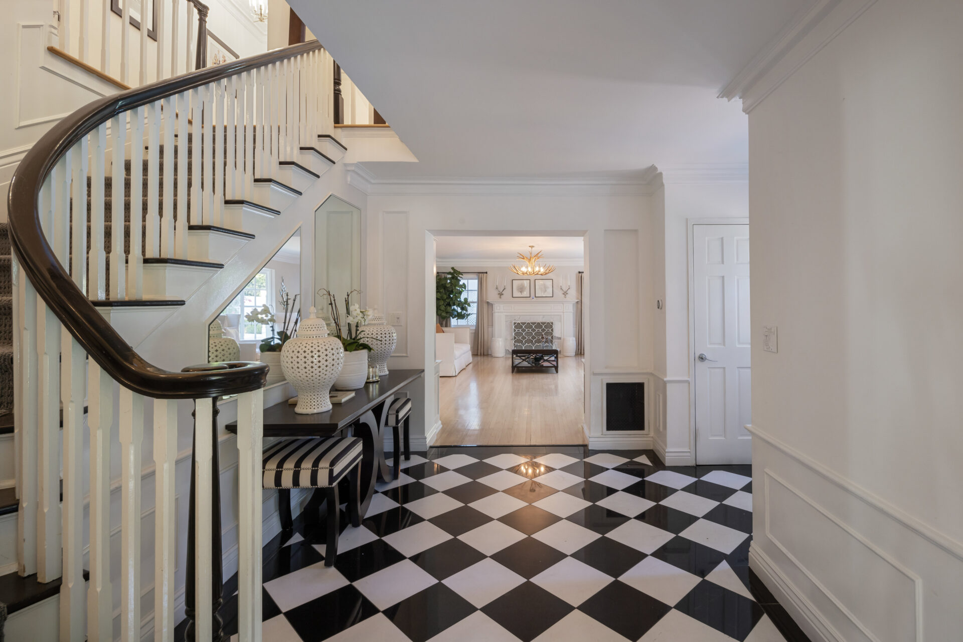 The foyer is laid with a black-and-white checkerboard floor and opens around a curved staircase.