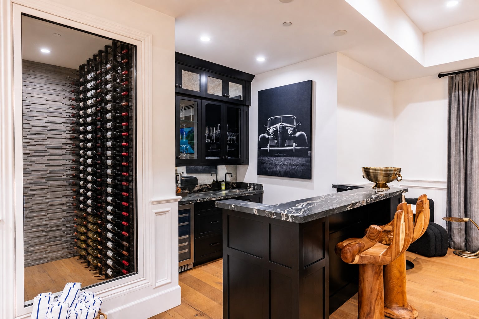 Tucked along the other side is a custom bar with black-and-white stone countertops and wood hand-shaped stools. 