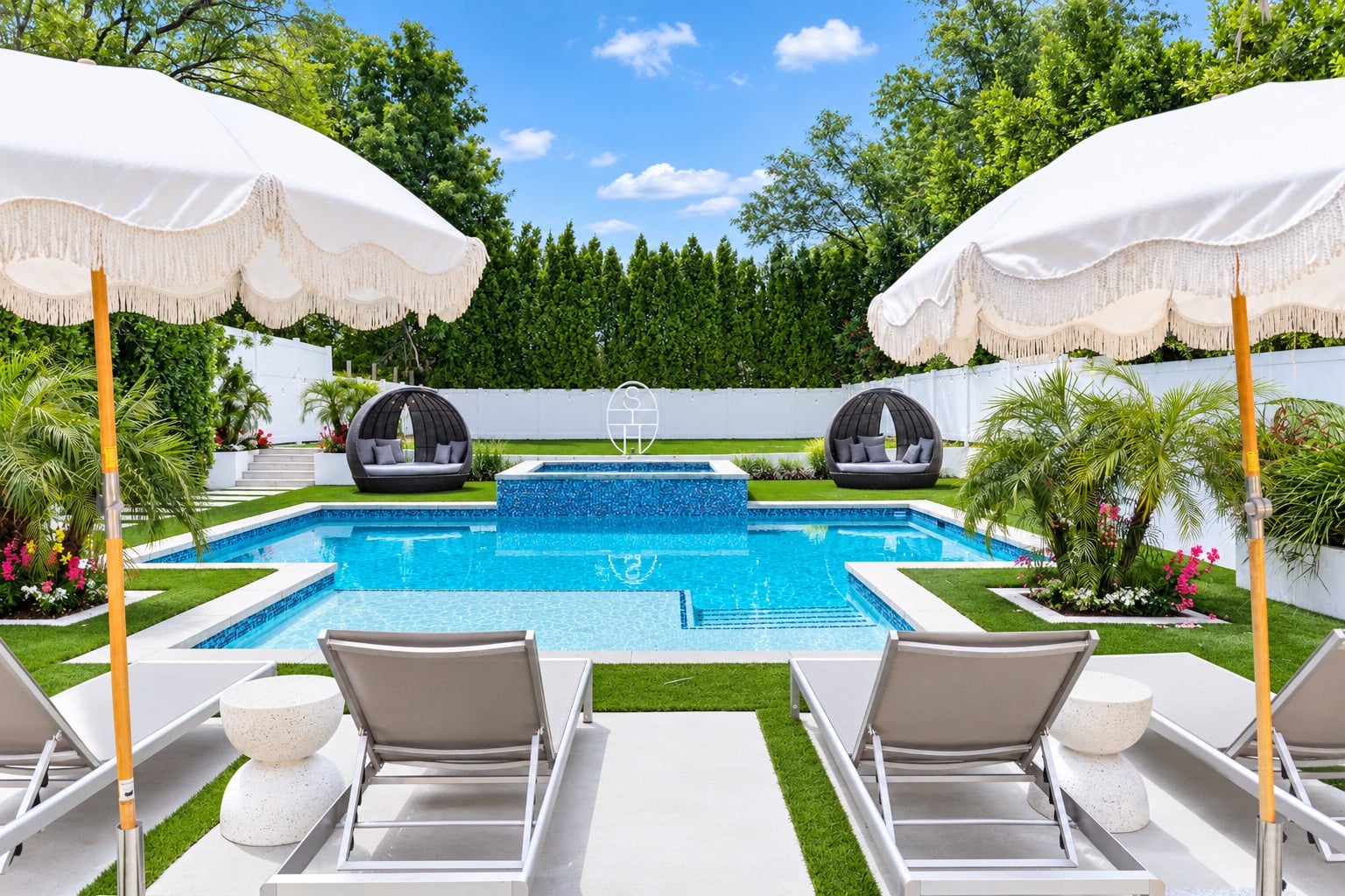 Beyond the patio, the yard opens to the pool and raised spa, where a cascading waterfall spills into the water below. 