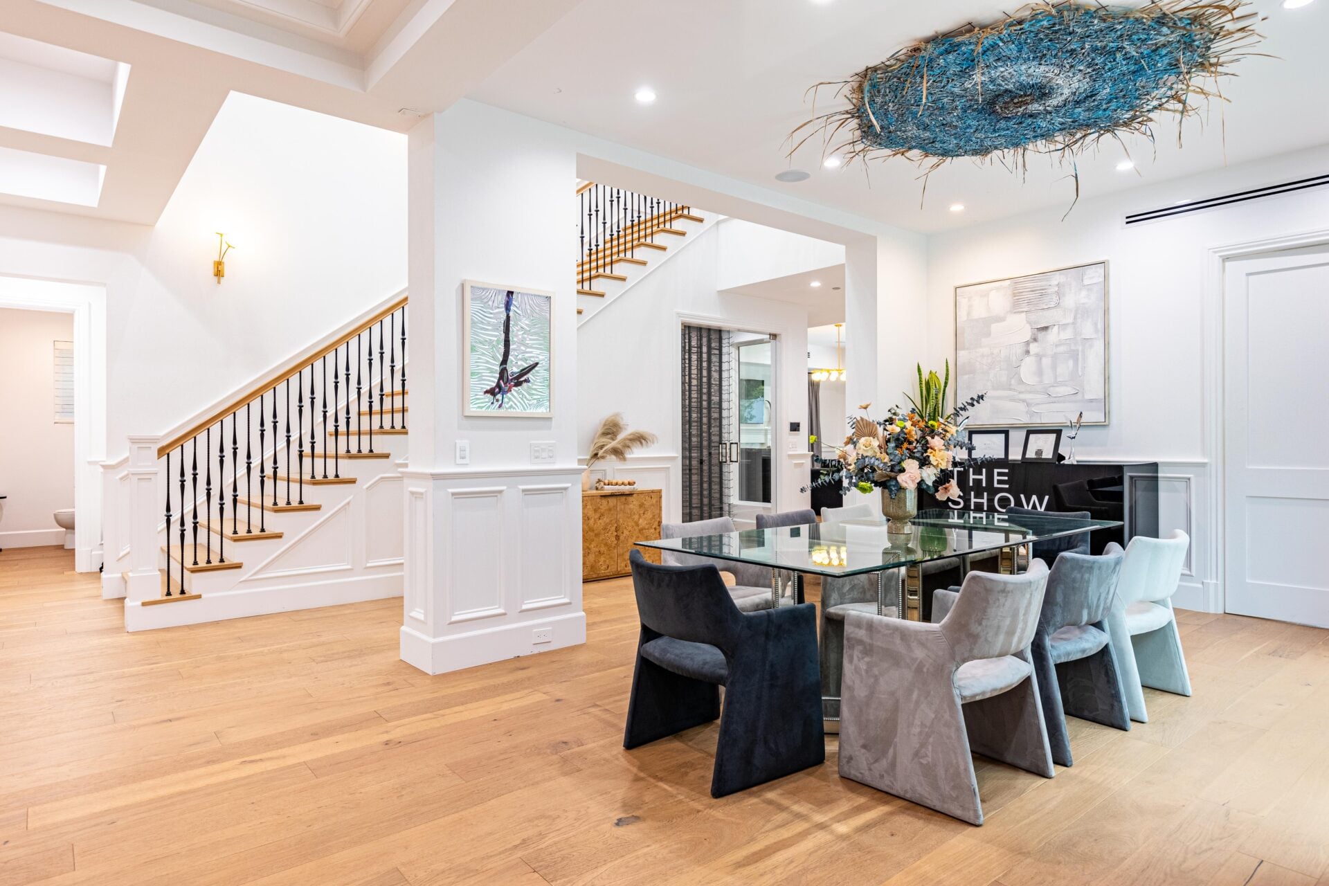 The dining area with a rectangular glass table surrounded by chairs in shades of gray, black, and white.
