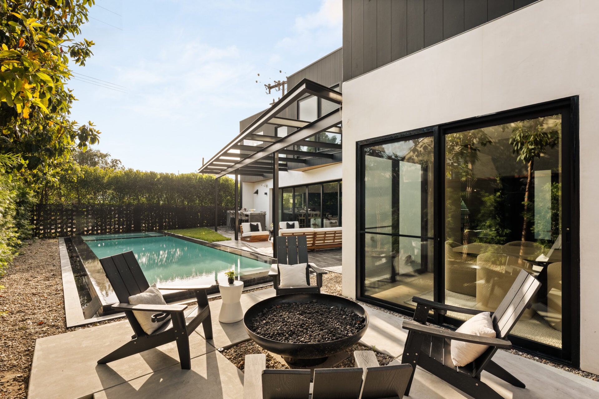 A separate patio creates another gathering area beside the pool with Adirondack chairs encircling a contemporary circular fire pit.