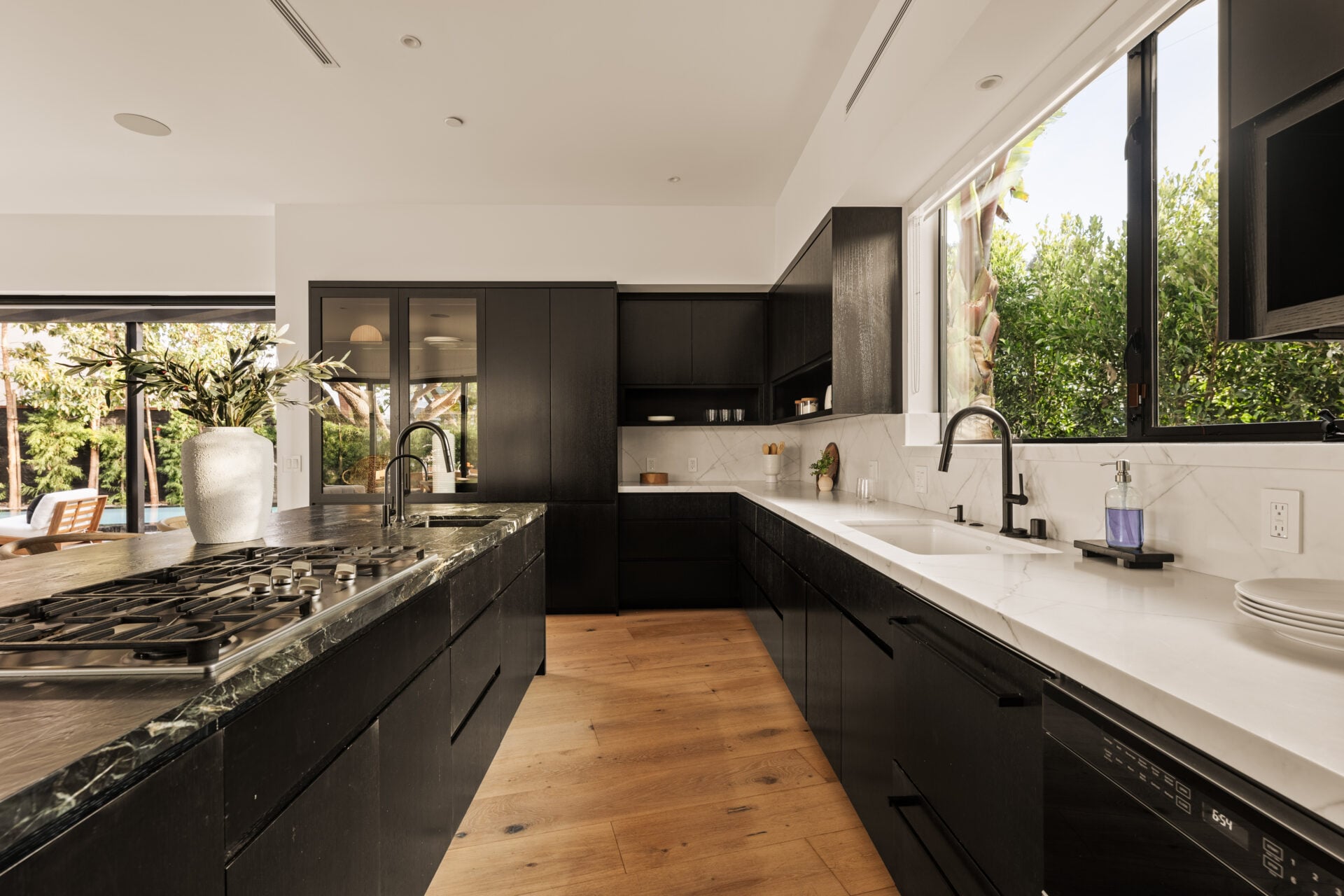 Custom dark cabinetry wraps the surrounding walls, with integrated Miele appliances set into the millwork and white perimeter counters.