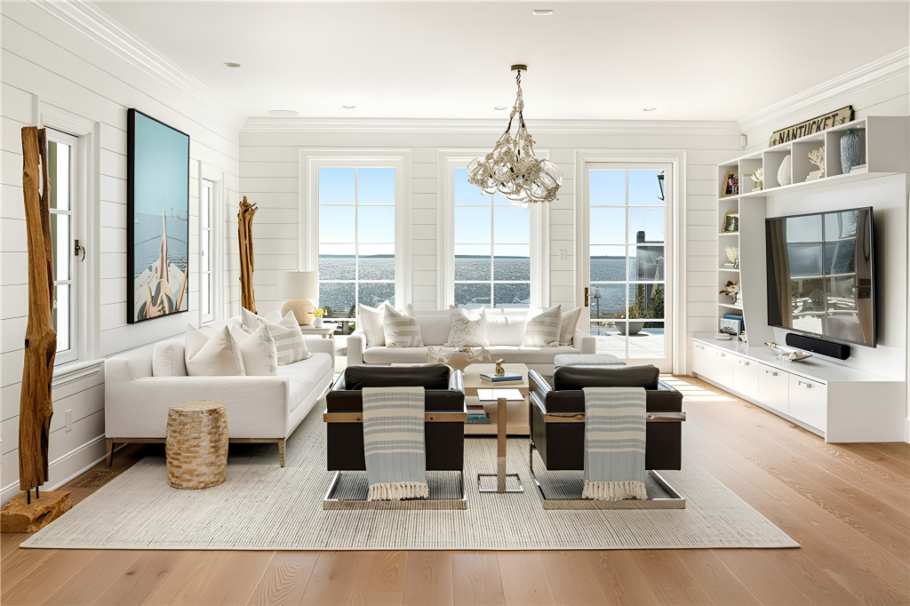 White sofas and a pair of darker leather chairs are grouped around a coffee table facing a media wall with built-in shelving framing the TV.