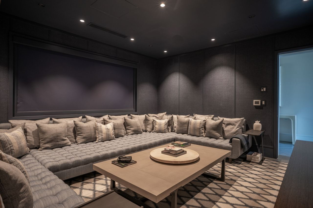 A blackout shade drops over the window to darken the space completely, allowing the room to transform into a dedicated home theater.