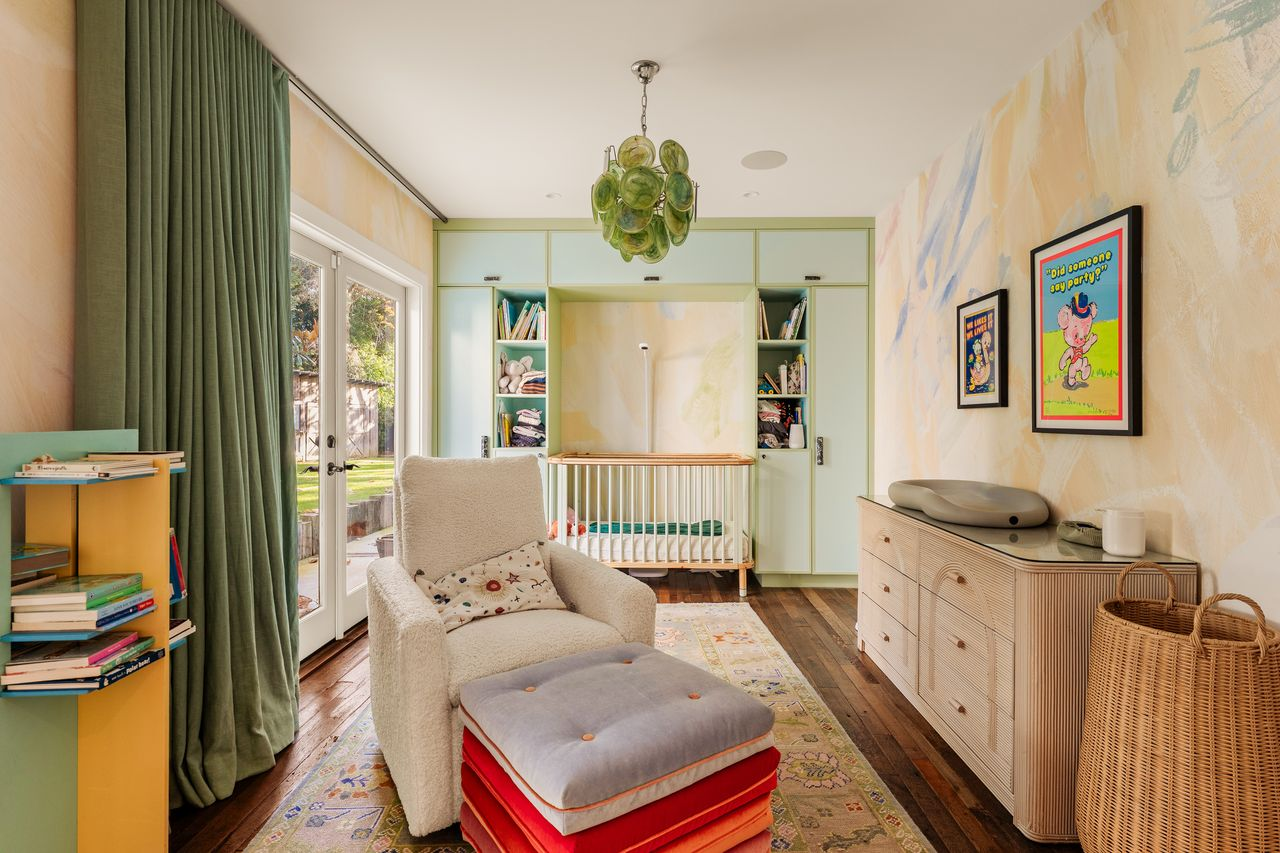 Built-in cabinetry wraps the far wall around the crib, while a soft armchair and ottoman create a separate spot for reading or feeding.