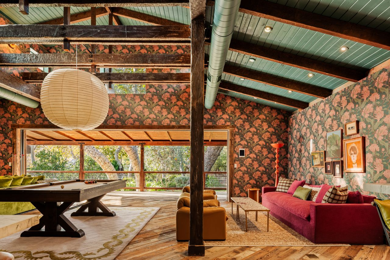 Pocket doors on one side of the room slide open to a long balcony overlooking the trees.