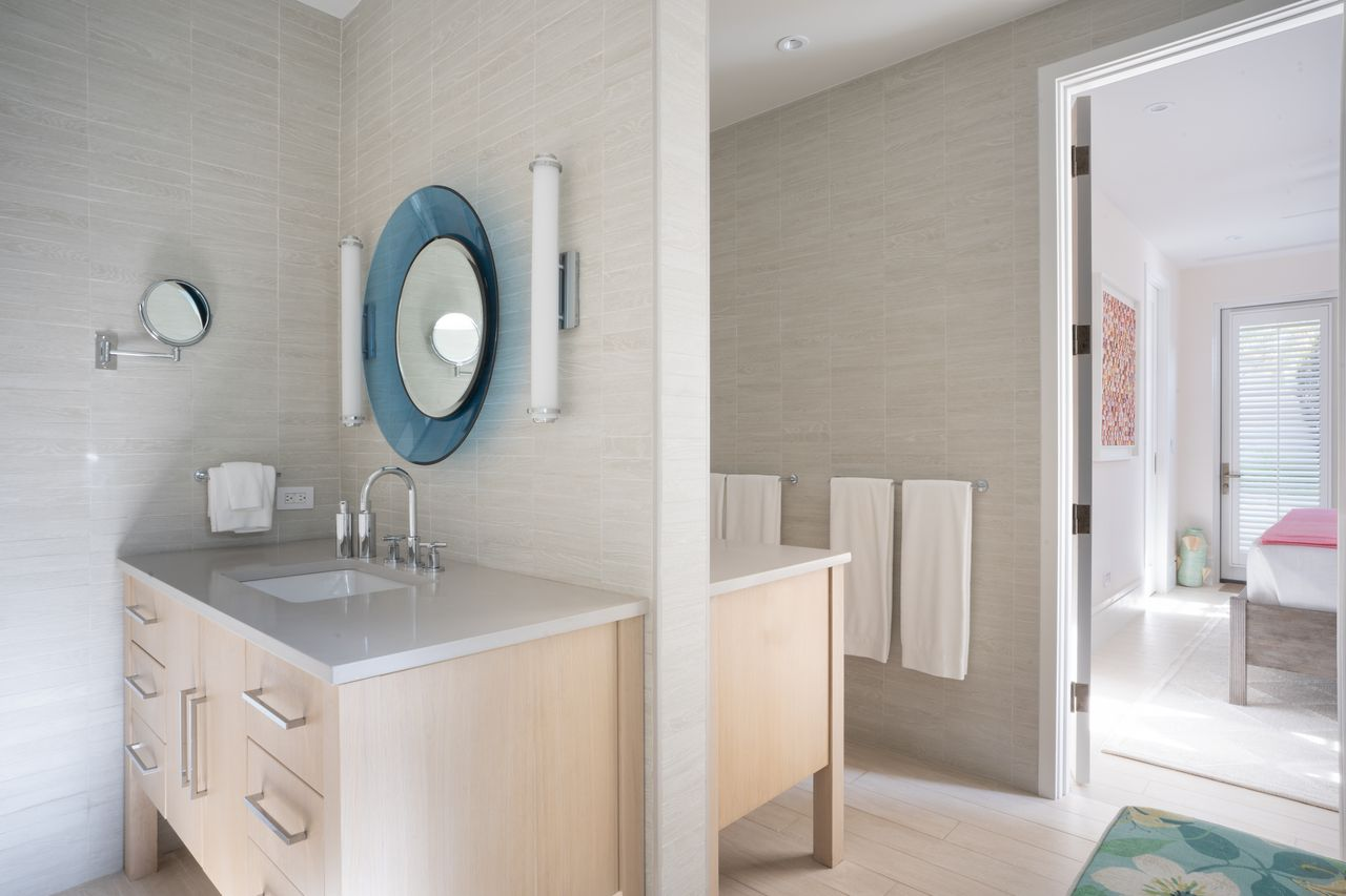 Its en-suite bathroom has two light wood vanities seperated by a wall lined in light-toned tile.