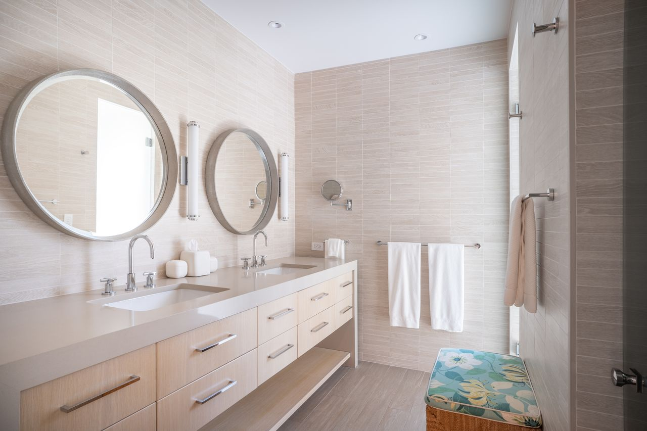 This suite's bathroom has a long double vanity with two round mirrors similar to the primary suite.