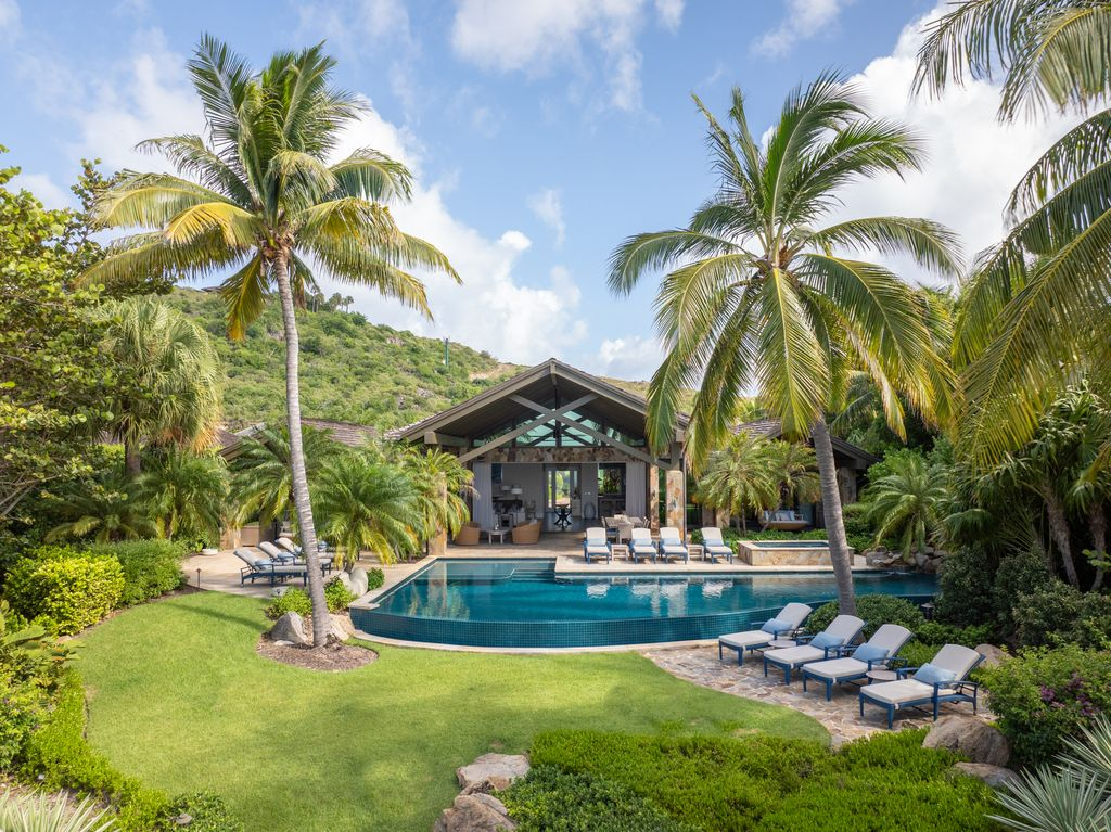 Past the covered terrace, the outdoor space opens to the open air with a heated infinity pool and hot tub surrounded by lounge chairs.