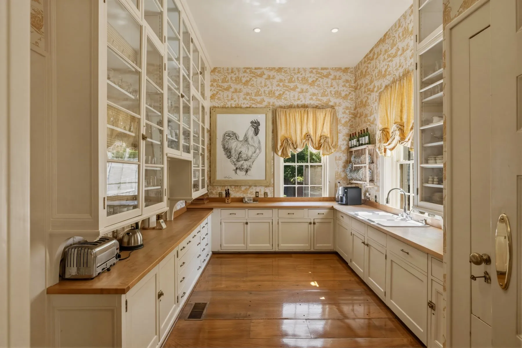Wood counters run beneath the windows, while the patterned wallpaper and gathered shades continue the more decorative design seen throughout this side of the house.