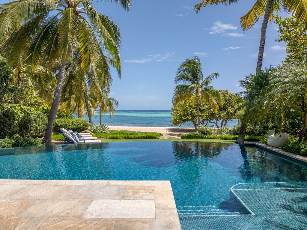From the pool, the grounds continue toward the villa’s white-sand beach.