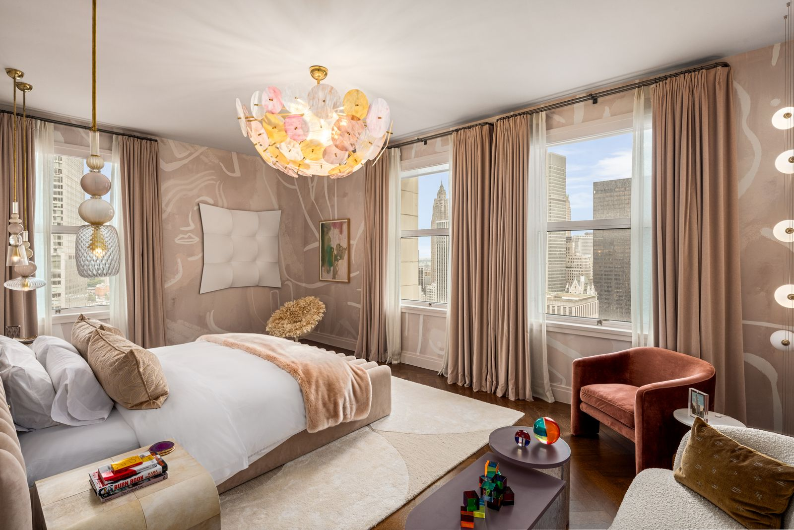 Within the suite, the bedroom sits against a pair of oversized windows framed by pink curtains, with the bed facing the skyline. 