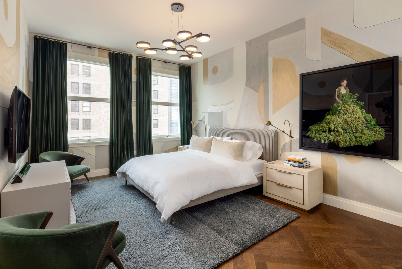 Behind the bed, the wall is covered in an abstract mural of oversized cream, pale gray, and muted gold shapes, giving the room a graphic backdrop that balance the more basic furniture.