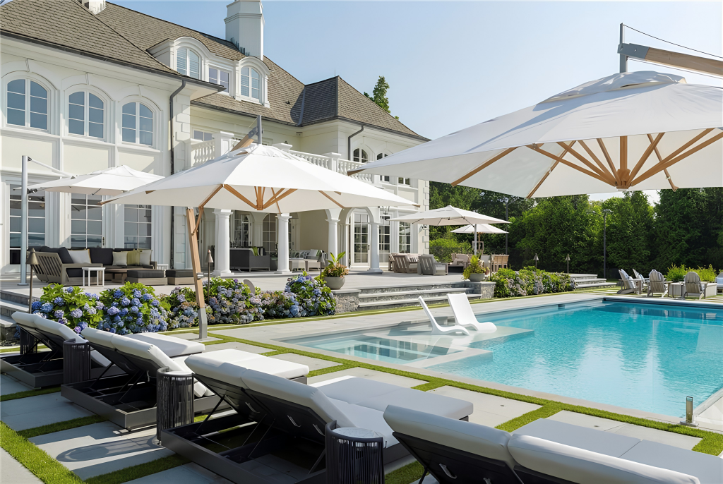 Wide stone decking surrounds the water with rows of loungers, while a shallow shelf at one end places additional seating directly within the pool.