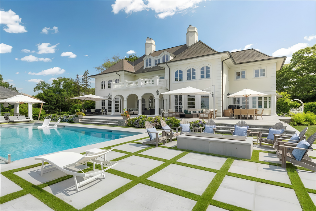On one side of the pool Adirondack chairs surround a long rectangular fire pit.