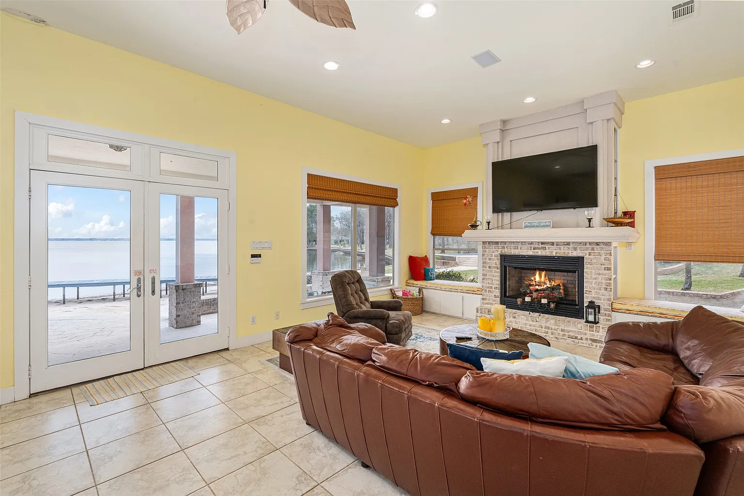 Stepping into the lower level, the living room opens with a large leather sectional wrapping around a brick fireplace and television. 
