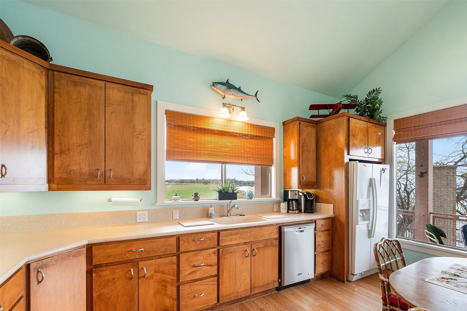Even the kitchen has the same layout but with a noticeably warmer design, with wood cabinetry and wood floors.