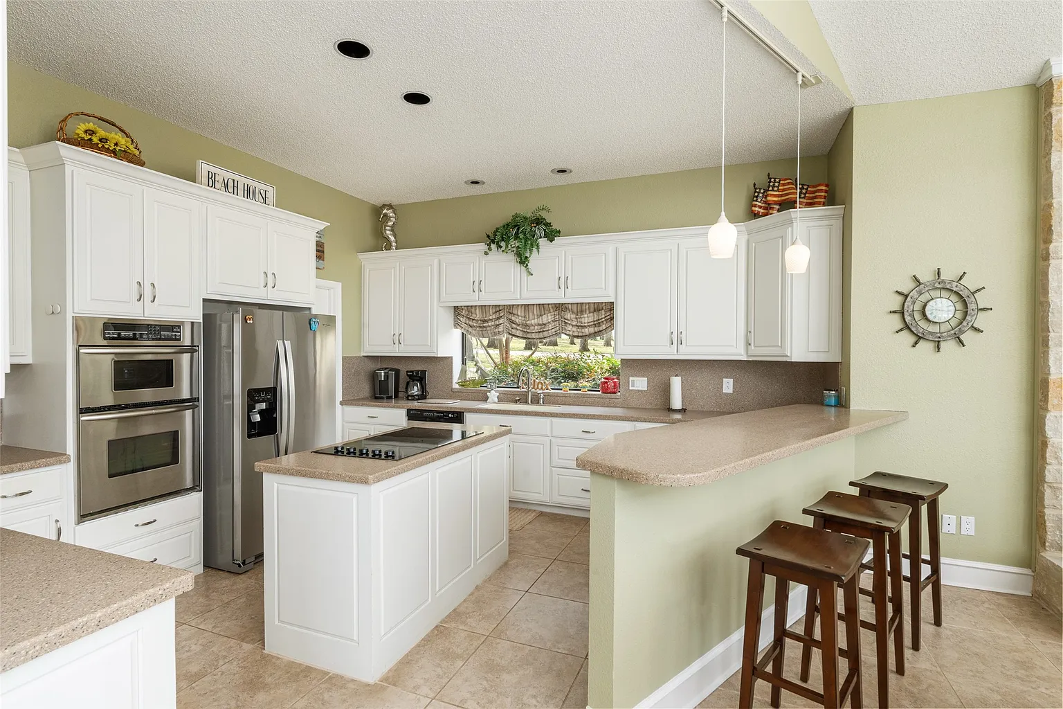 White cabinetry wraps around the back and side walls, while a compact center island is topped with the gas stove facing the lake.