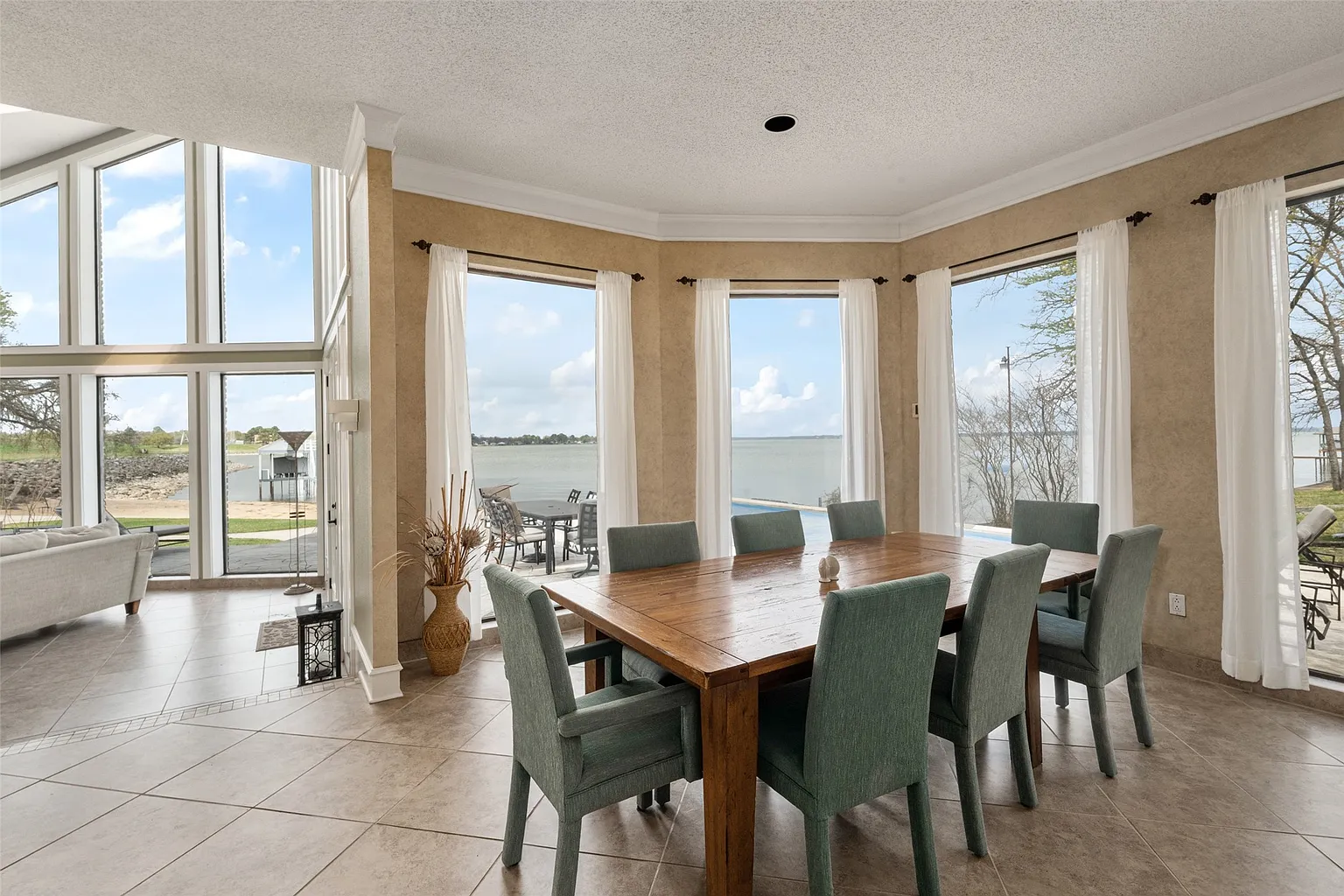 In the center, a long wood table is surrounded by eight cushioned chairs.