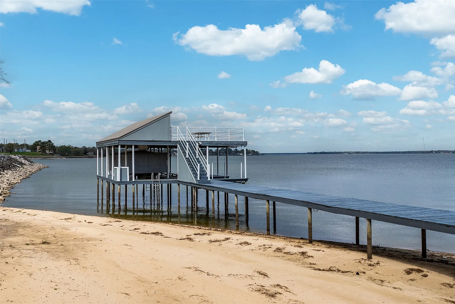 A path leads down to the property's 100 feet of shoreline, where a private dock extends the walkway to a covered boathouse equipped with a boat lift. 