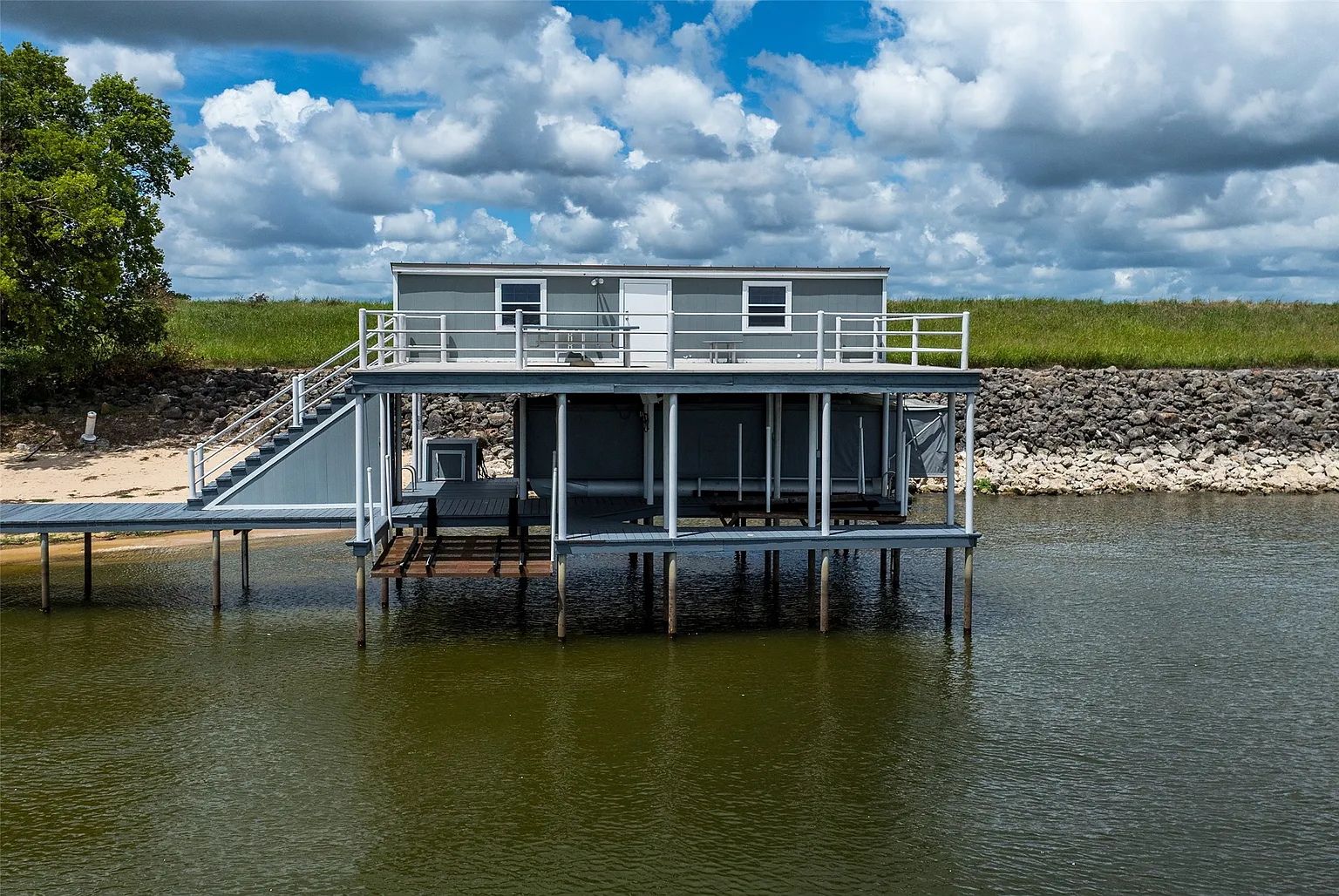 An upper deck sits above the covered slip, while the long pier provides direct access out onto Cedar Creek Lake from the property’s shoreline.