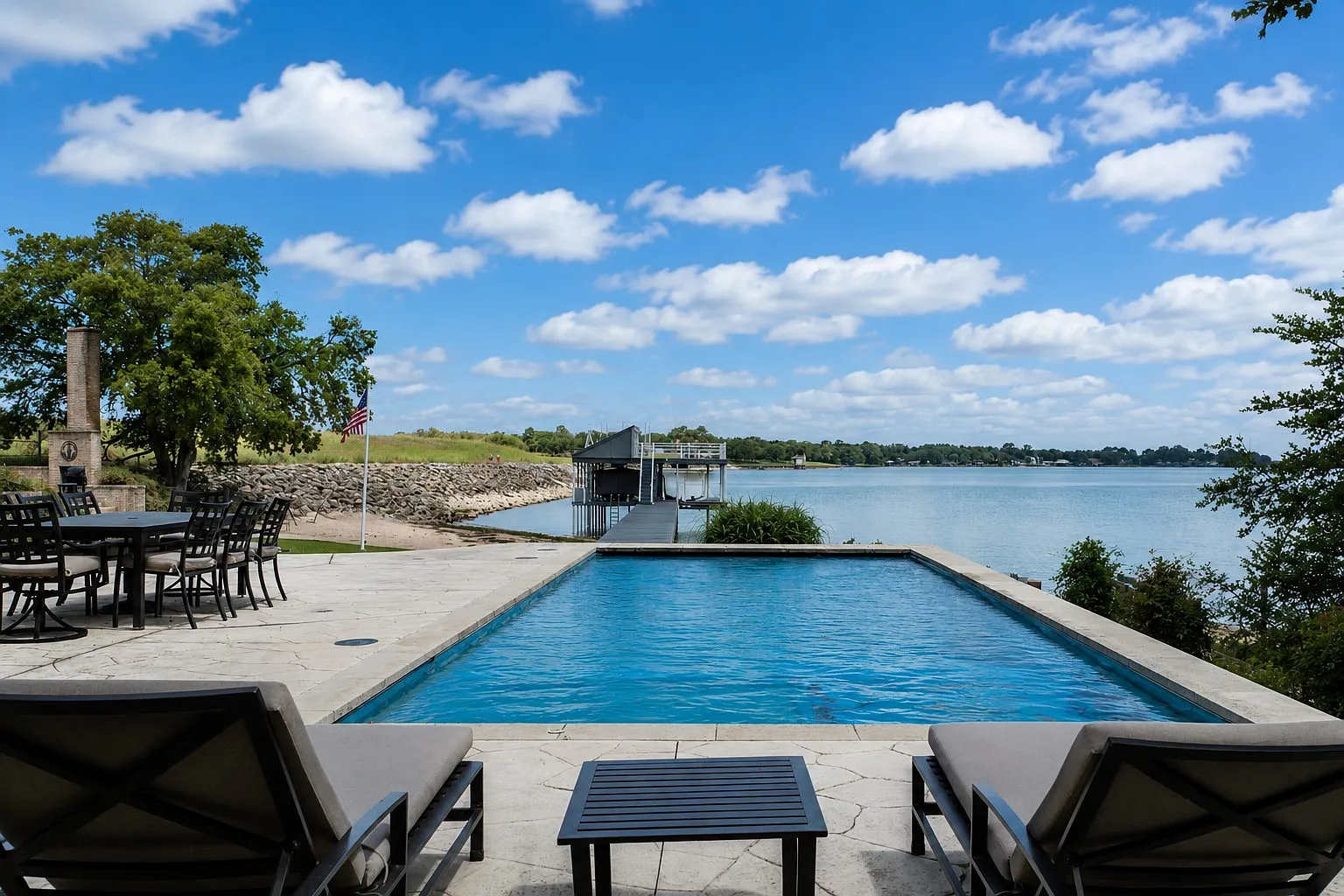 The pool stretches along the waterfront side of the house, surrounded by a patio with space for lounge chairs and outdoor dining.