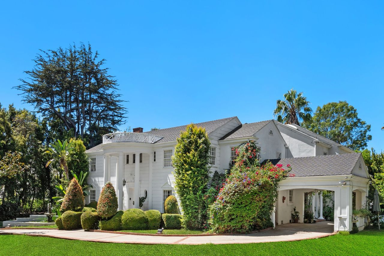 Continuing past the front entrance, the drive wraps around the right side of the house and passes beneath a covered porte-cochère.
