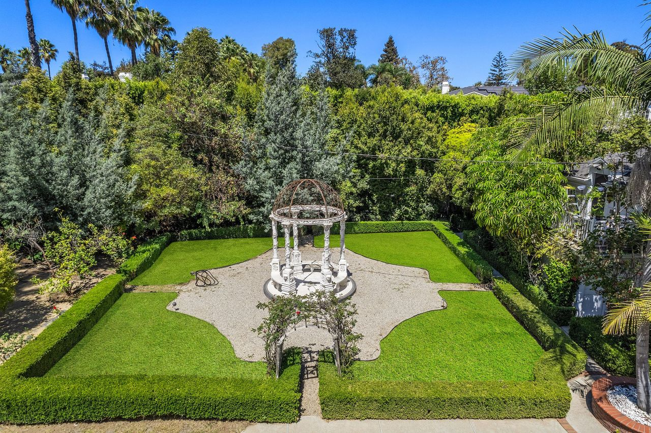 Off to one side of the backyard, low hedges create an enclosed square around the garden gazebo, surrounded by gravel and grass.