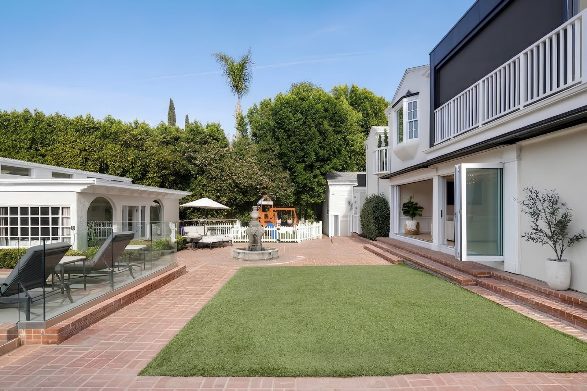 Directly behind the main house, a brick patio extends across the courtyard toward the detached guest house. 
