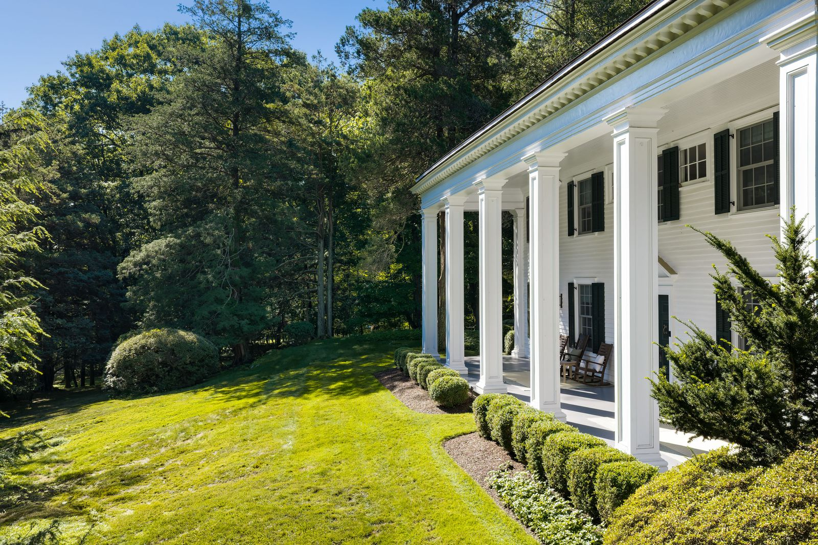 A large lawn stretches out in front of the white Southern Colonial exterior.