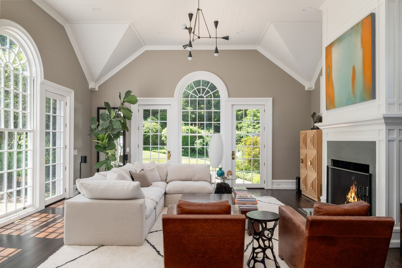 The large great room, capped by a cathedral ceiling with white-painted paneling that follows the room’s steep roofline. 