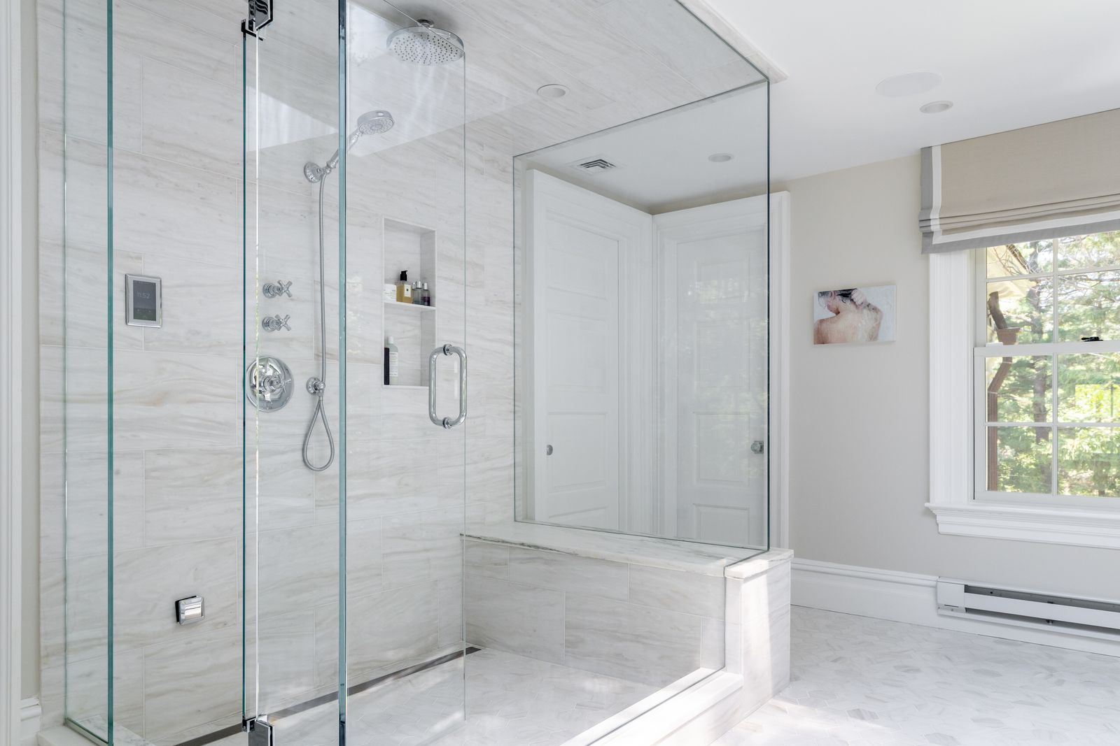 A glass-enclosed steam shower is placed across from the tub.