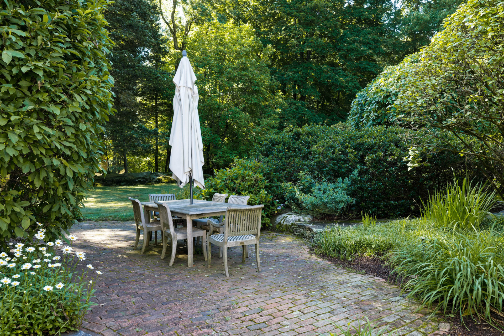 Outdoor dining table surrounded by greenery.
