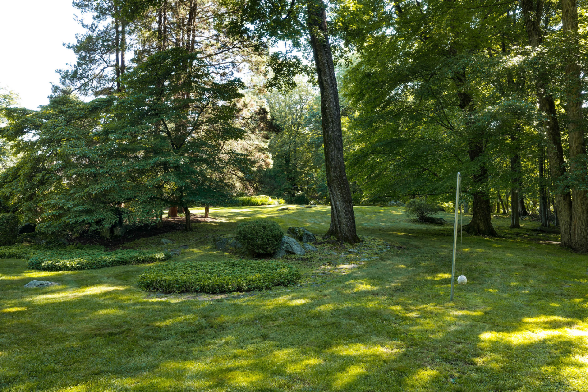 The property opens into large stretches of lawn that slope gently through the trees.