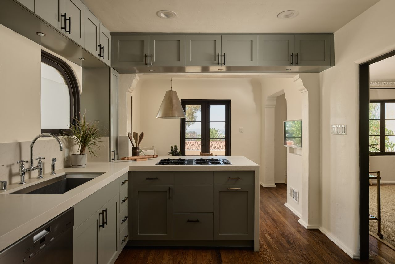 From the dining areas, the layout moves directly into the kitchen, where gray shaker-style cabinetry wraps the room around white countertops. 
