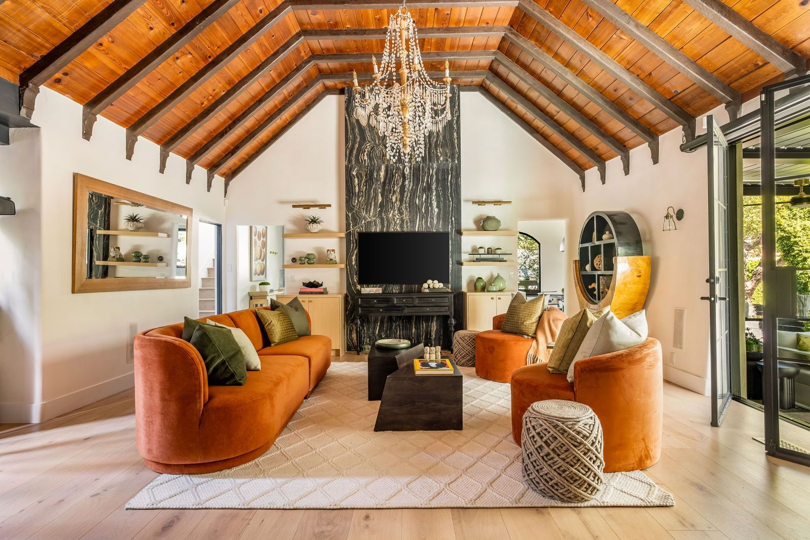 Custom built-in shelving surrounds the TV, while orange velvet sofas and chairs sit in front of it.