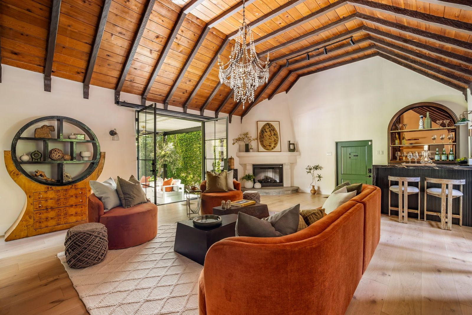 Across the room, a small green door sits in the middle of an oversized fireplace and a custom bar.