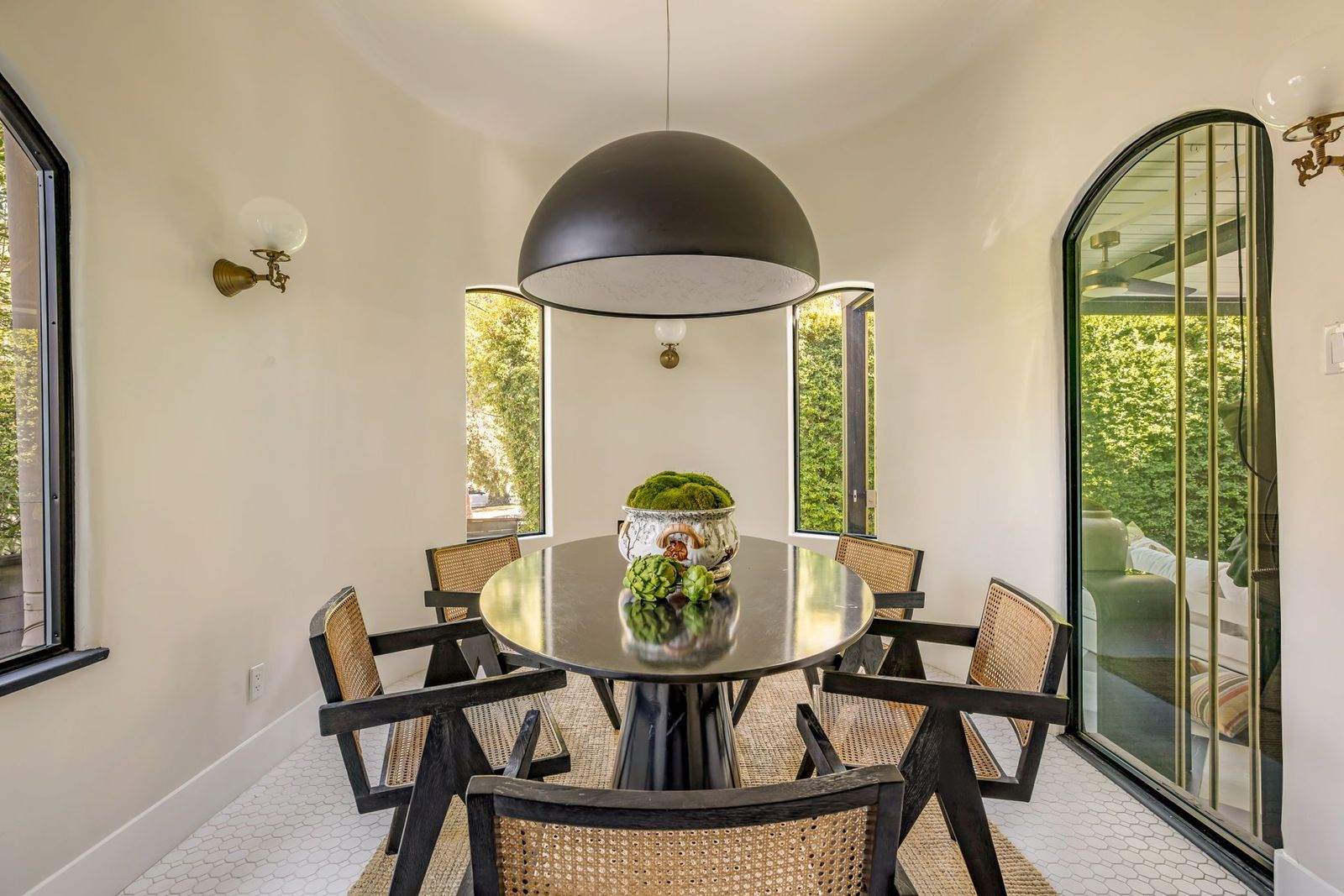 Connected directly to the sunroom via an arched glass door, the turret-style dining room is lined with tall, narrow arched windows.