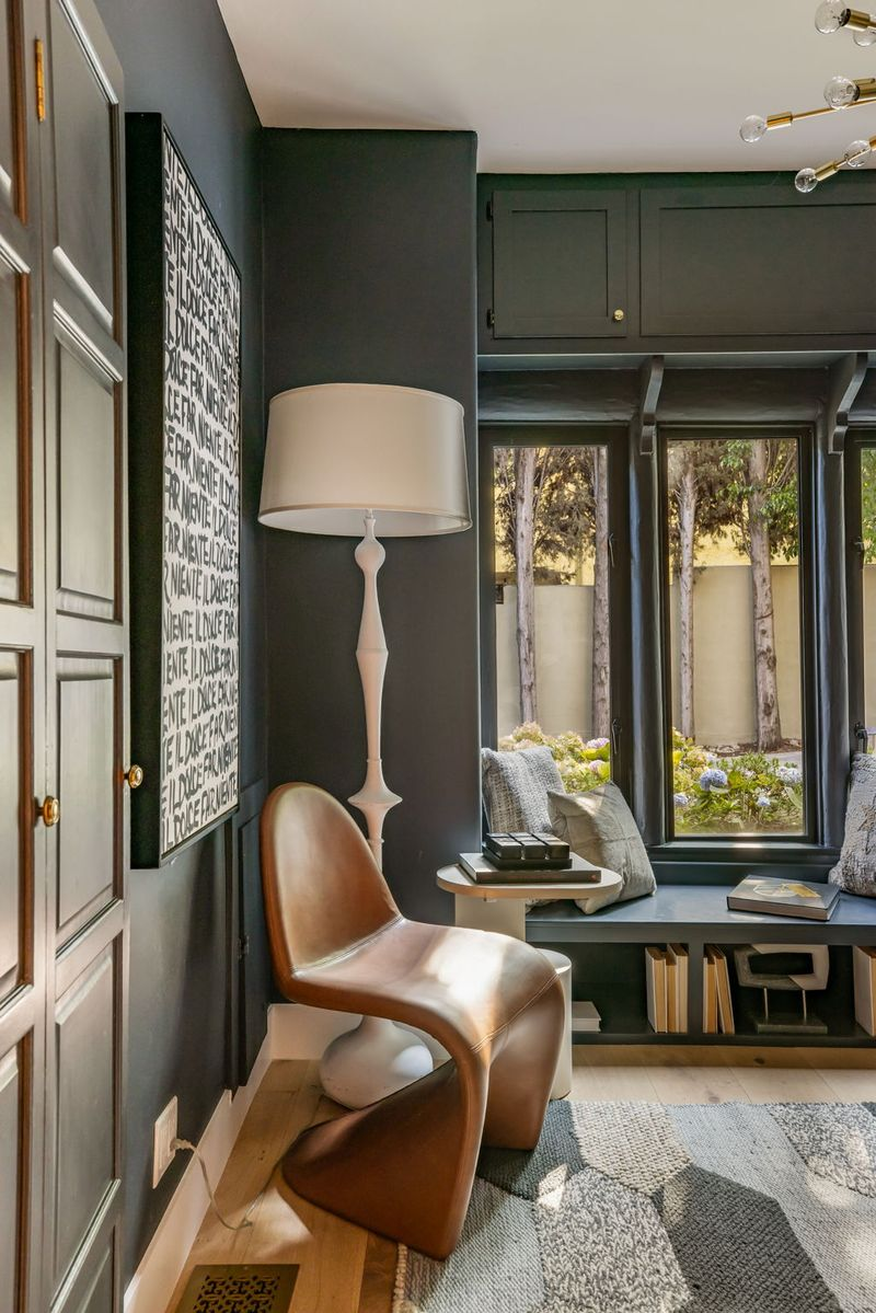 Across from the desk, a built-in window seat with storage underneath stretches beneath a row of tall windows.