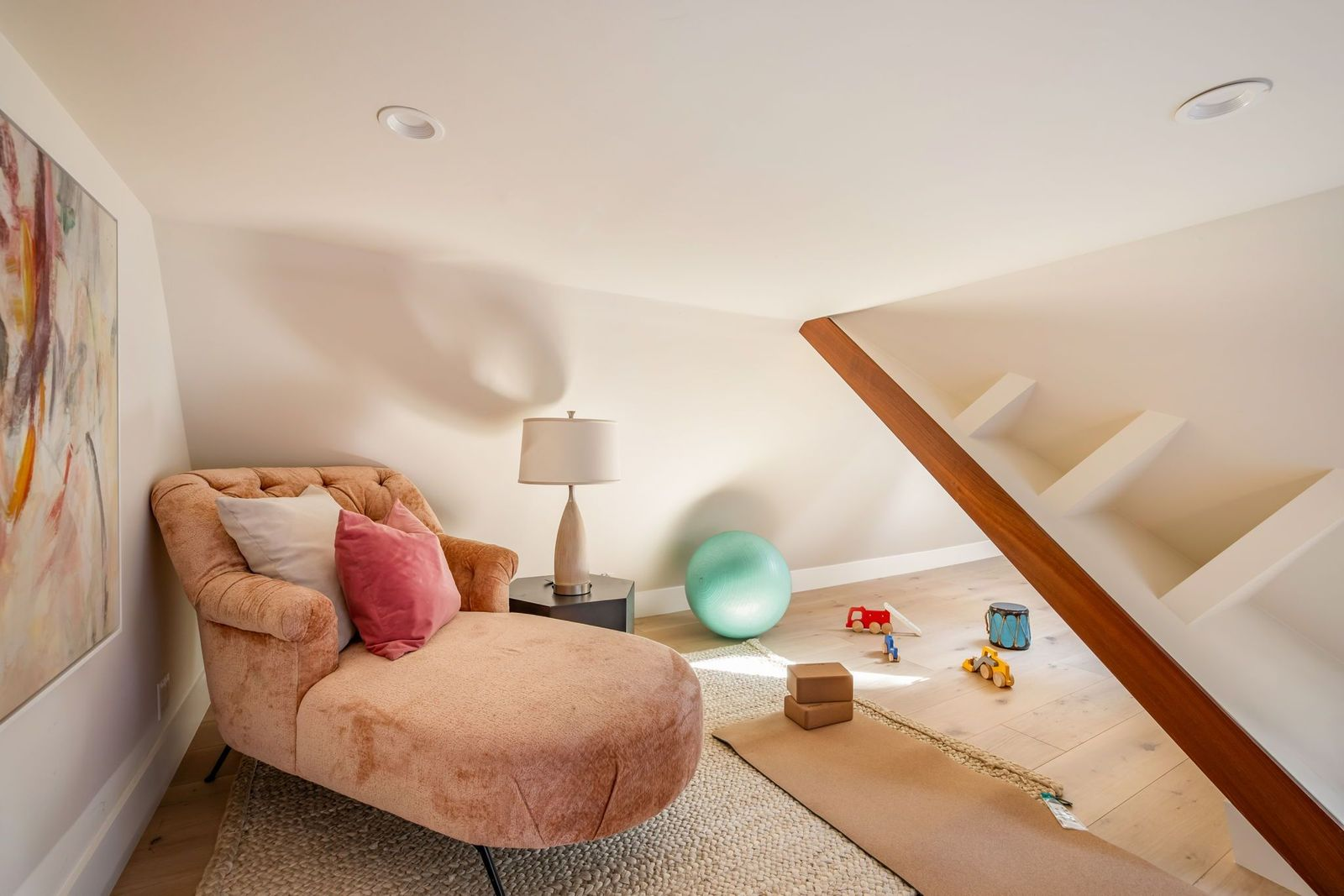 A compact bonus room is tucked beneath the sloping roofline, with light wood floors and angular walls