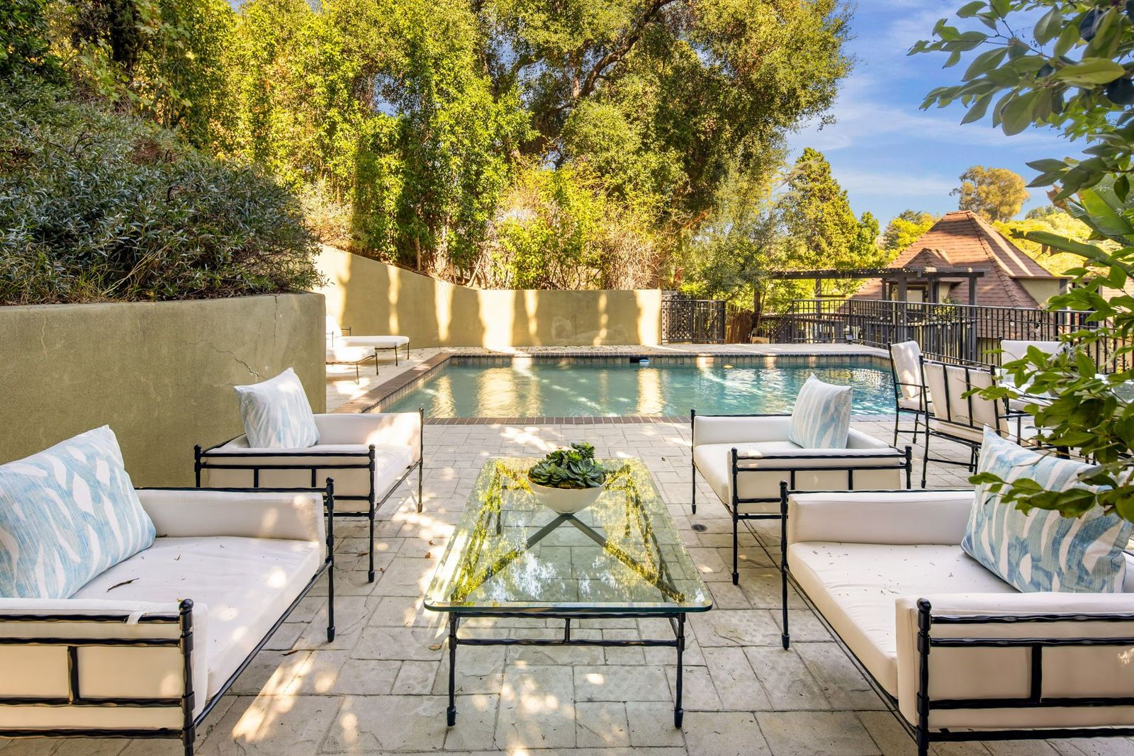 Placed slightly farther back, another seating area with four cushioned chairs and a long glass coffee table overlooks the water.