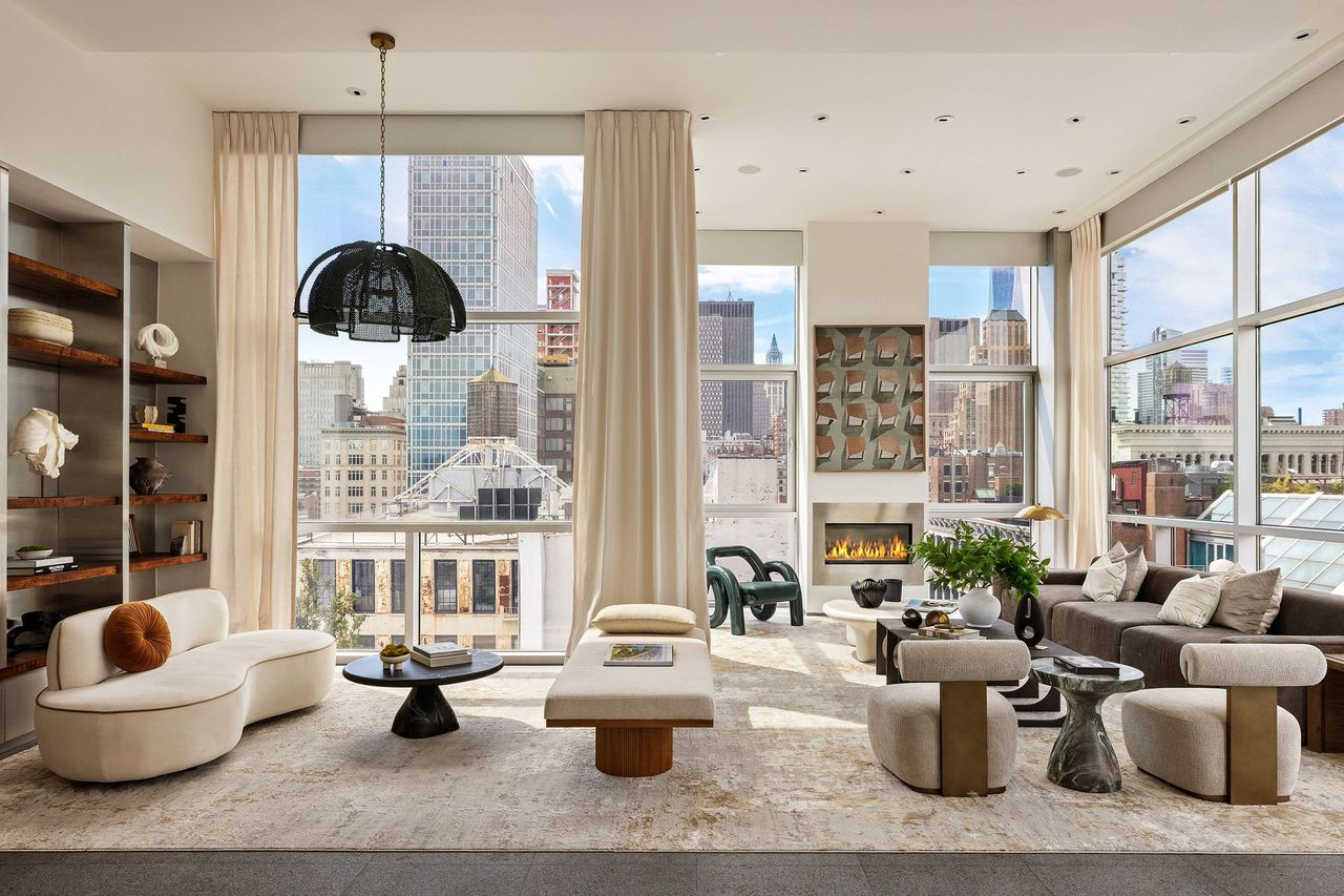 A large great room beneath 14-foot ceilings and glass walls with views of Manhattan.