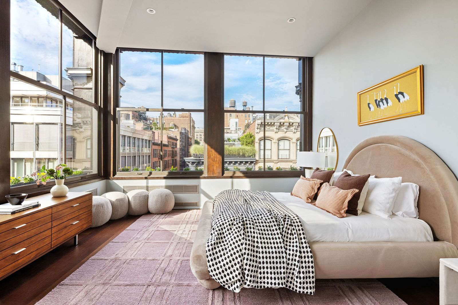 A full-size guest room, with an upholstered bed placed beside corner windows.