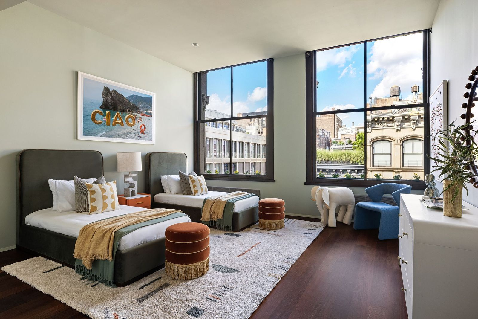 Two twin beds beside tall windows overlooking Broome Street.