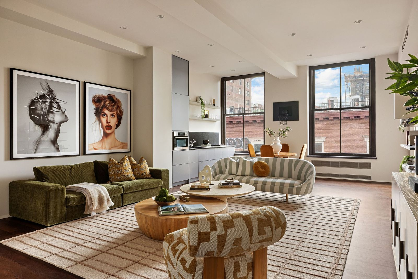 One side of the room is made up of a variety of couches and chairs with a small kitchen on the other.