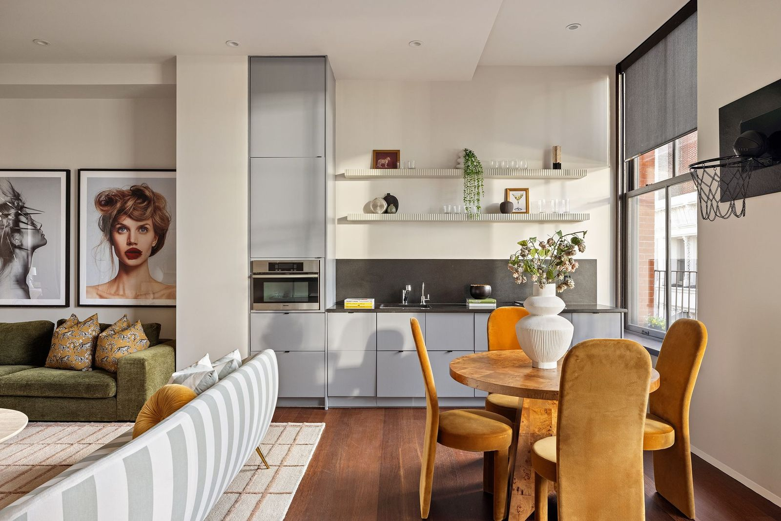 A compact kitchen with streamlined cabinetry, open shelving, a sink, and integrated appliances. 