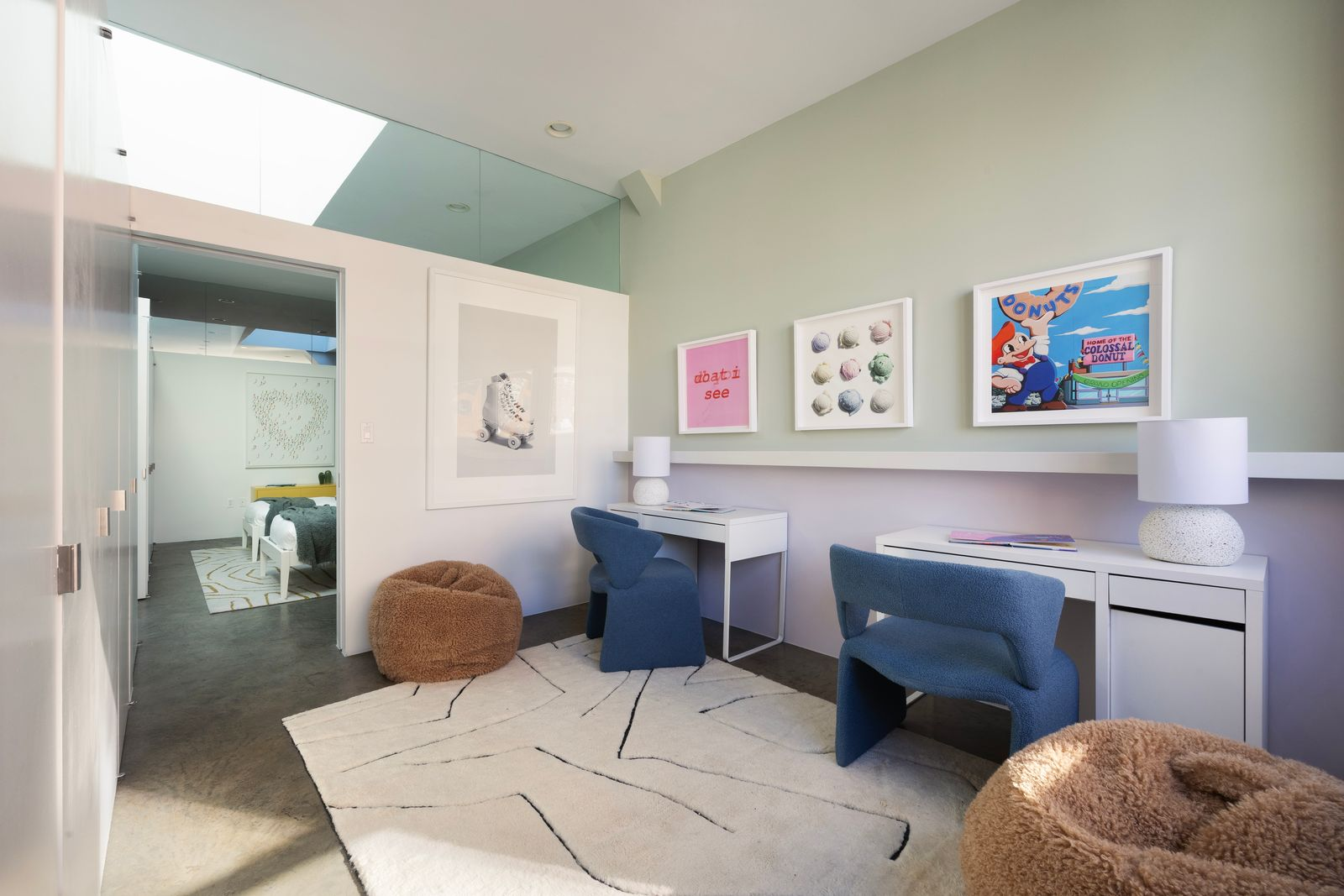 In the next room, the suite opens into a connected study space with two desks placed beneath framed artwork.