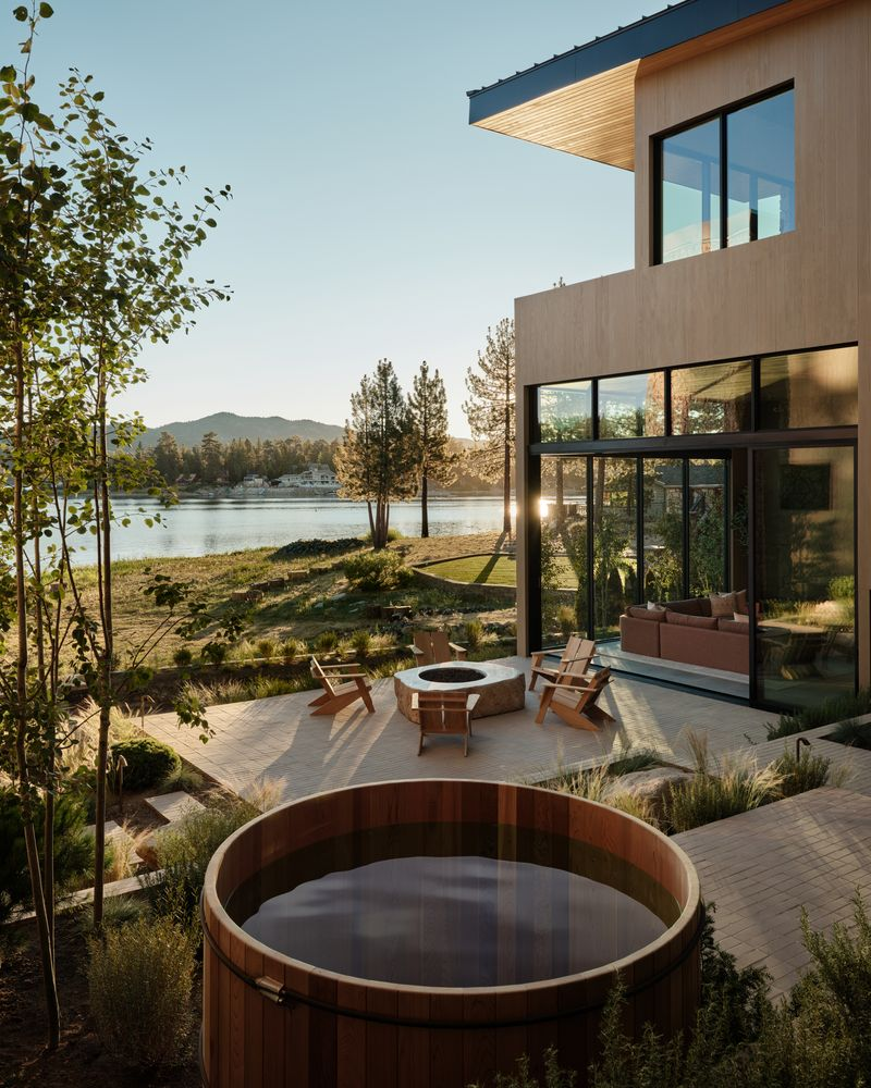 A cedar soaking tub sits beside the path before the courtyard opens to a custom fire pit positioned closer to the water. 